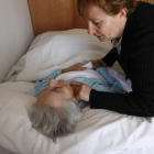 Una anciana dependiente recibe cuidados de una familiar en su casa.