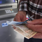 Un hombre muestra dinero tras pasar por un cajero automático. KATIA CHRISTODOU