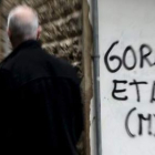 Un hombre pasa junto a una pintada de apoyo a ETA en una calle de San Sebastián.
