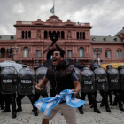 Un seguidor de Diego Armando Maradona ante un grupo de efectivos de la Policía a las puertas de la Casa Rosada. JUAN IGNACIO RONCORONI
