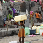 Una niña huérfana carga con un bidón para el agua en Bombai (India).