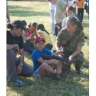Una soldado enseña a una niña a coger una escopeta
