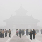 Varias personas pasean bajo una espesa capa de bruma por los alrededores del Templo del Cielo en Pekín.