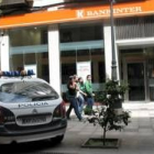 El vehículo policial aparcado enfrente de la entidad financiera
