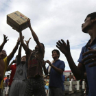 Varios lugareños toman una caja robada del interior de un contenedor de comestibles forzado por varias personas en la ciudad de Tacloban