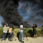 Unos periodistas toman imágenes de la gran columna de humo producida este viernes en un polígono de Chiloeches, Guadalajara.