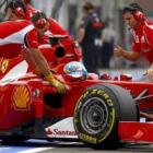 Fernando Alonso conduce su monoplaza, ayudado por los mecánicos, rumbo a boxes.
