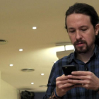 El secretario general de Podemos, Pablo Iglesias, mira su móvil antes de comparecer ante los medios, este jueves.