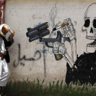 Un hombre camina junto a un grafiti antitabaco.