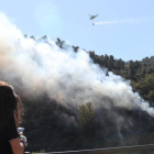 Uno de los cuatro helicópteros que sofocan el fuego en el monte Pajariel tira agua sobre la zona en llamas.