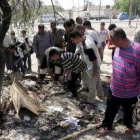 Varios iraquíes observan el lugar de la explosión de un coche bomba