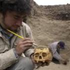 Un arqueólogo limpia la calavera de una momia
