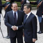 El primer ministro italiano, Berlusconi, estrecha la mano del presidente francés, Sarkozy.