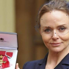 La diseñadora Stella McCartney muestra la medalla tras recibir el título oficial de la Orden del Imperio Británico.