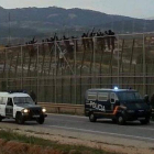 Algunos de los subsaharianos, encaramados en lo alto de la valla de Melilla, este viernes.
