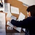 Una joven mira las ofertas de empleo en un tablón de anuncios de una oficina del Inem