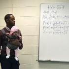 Imagen del profesor con el bebé, en plena clase.