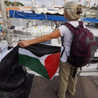 Una activista con la bandera palestina frente a uno de los dos veleros de la flotilla que ha partido hacia Gaza.