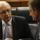 El ministro de Hacienda, Cristóbal Montoro, conversa con el presidente del Gobierno, Mariano Rajoy, este martes durante el debate sobre los Presupuestos en el Congreso.
