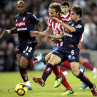 Forlán, que se lesionó, trata de llevarse el balón ante dos jugadores del Sporting de Gijón.