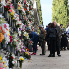 Un grupo de persona coloca flores en los jarrones de los nichos del cementerio.