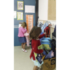 Dos niñas colocan sus mochilas al llegar a clase.