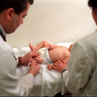 Dos sanitarios vacunan a un bebé en un ambulatorio.