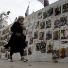 Una mujer israelí pasa junto a un muro con imágenes.