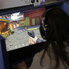 Una joven juega con una pistola virtual frente a la pantalla de un videojuego.