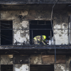 Bomberos y Policía Científica inspeccionan un cuerpo en un balcón del edificio incendiado.
