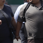 Fotografía de archivo que muestra a dos personas con obesidad mientras caminan.