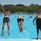 Tres jóvenes se lanzan a la piscina en una intensa jornada de calor veraniego. KIKO HUESCA