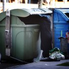 Una persona busca en un contenedor de basura