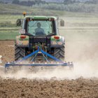 Un agricultor labra con tractor la tierra, donde la escasez de lluvias y las altas temperaturas provocan una gran polvareda