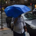 Un hombre pasea por León en un día de lluvia y viento