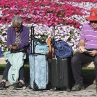 Dos viajeros jubilados descansan en un banco antes de empreder viaje.