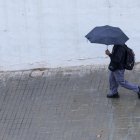 Un joven se protege de la lluvia con un paraguas en Valencia, en una imagen de archivo. EFE/Kai Försterling