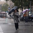 Una mujer se protege de la lluvia en el centro de Barcelona este lunes cuando las comarcas de del Garraf y del Barcelonès, en Barcelona, están en aviso rojo de la Agencia Estatal de Meteorología (Aemet), y la Generalitat ha enviado una alerta a los teléfonos móviles por la llegada de lluvias continuadas y torrenciales. EFE/Alberto Estévez