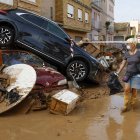 Los vecinos limpian las calles junto a varios coches apilados en Catarroja, Valencia este martes, una de las localidades más afectados por las inundaciones. EFE/ Chema Moya