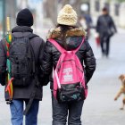 Dos jóvenes pasean muy abrigados por la calle.