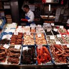 Aspecto que presenta un puesto de venta de pescado en el mercado del Ensanche de Pamplona, este lunes, donde varias personas ultiman la compra de los alimentos que estarán sobre la mesa en estas fiestas de Navidad.