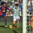 El defensa francés del FC Barcelona Jules Koundé (i) disputa un balón con el delantero hispano-marroquí del Betis Ez Abde (c) durante el partido de la jornada décimo sexta de LaLiga EA Sports que disputaron Real Betis Balompié y FC Barcelona en el Estadio Benito Villamarín de Sevilla. EFE/ Raúl Caro