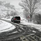 Un coche se desplaza en una carretera nevada.