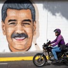 Un motociclista pasa frente a un mural del líder chavista Nicolás Maduro este martes, en Caracas (Venezuela). EFE/ Ronald Peña R.