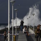 Turistas y donostiarras observan el oleaje en la playa de la Zurriola de San Sebastián.