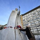 Una mujer pone flores en la estatua de Juan Pablo II en el hospital Gemelli.