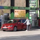 Una mujer reposta gasolina en una estación de servicio.