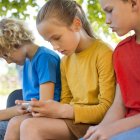 Tres niños jugando con su teléfono móvil.