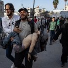 Un hombre lleva el cuerpo de su hijo, muerto en un ataque aéreo israelí.