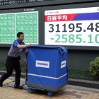 Un repartidor pasa junto a un panel de indicadores del índide bursátil Nikkei.